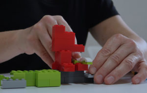 Sichtbar sind die Hände einer Person, die ein LEGO-Modell® baut.