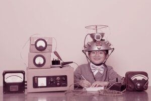 kleiner Junge sitzt vor improvisiertem Messgerät mit Funkstation auf dem Kopf am Tisch